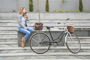 young woman bicycle rider use cellphone, urban background photo