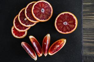 sliced sicilian or bloody oranges on a black slate background photo