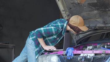 Mécanicien féminin réparant une voiture dans un garage video