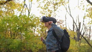 mujer joven feliz con gafas de realidad virtual divirtiéndose en el parque de otoño