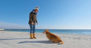 jonge vrouw speelt met corgi-hond op het zeestrand video