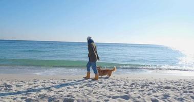 jovem brincando com cachorro corgi na praia