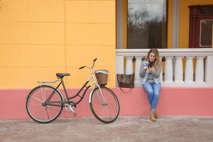 young woman bicycle rider use cellphone, urban background photo