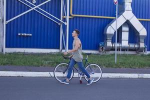 Young ,man walk with fixie bike, urban background, picture of hipster with bicycle in blue colors photo