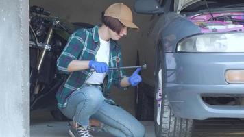 vrouwelijke monteur die auto in een garage repareert video