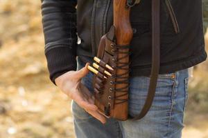 Male training with pump action shotgun outdoors in field. photo