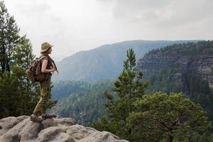 mujer joven caminando por el prado de primavera, las montañas y el bosque en el fondo foto