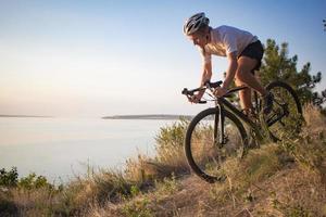 ciclista en bicicleta ciclocross profesional cuesta abajo, fondo de pino y lago