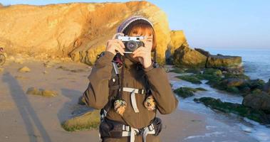 joven viajera con mochila y cámara de cine retro viaja en las montañas de otoño cerca del mar foto