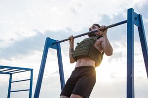 joven atleta barbudo entrenando al aire libre con chaleco ponderado, ejercicio con portador de placa militar foto
