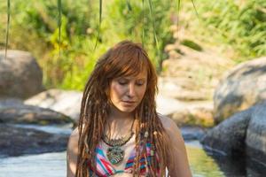 Young beautiful female with dreadlocks swim in mountain river in summer time, redhead woman in the pond photo