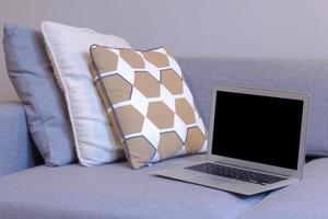 laptop in bedroom with bed, lamp and home decor background. photo