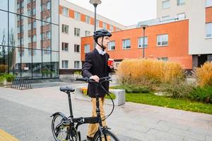 joven hombre de negocios con bicicleta y taza de café o té caminando al aire libre foto