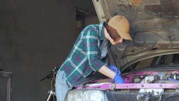 Mécanicien féminin réparant une voiture dans un garage video