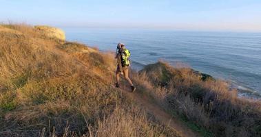 joven viajera con mochila y cámara de cine retro viaja en las montañas de otoño cerca del mar video