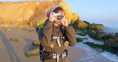 joven viajera con mochila y cámara de cine retro viaja en las montañas de otoño cerca del mar video