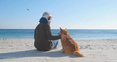 junge Frau spielt mit Corgi-Hund am Meeresstrand