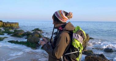 jovem viajante feminina com mochila e câmera de filme retrô viajar nas montanhas de outono perto do mar