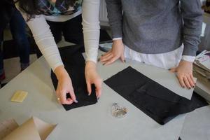 costurera en el trabajo sobre la mesa, sastre mujer trabaja en estudio con ropa foto