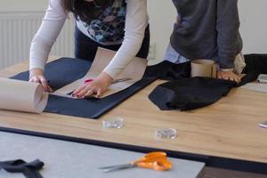 costurera en el trabajo sobre la mesa, sastre mujer trabaja en estudio con ropa foto