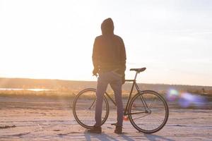 Alone rider on fixed gear road bike riding in the desert near river, hipster tourist bicycle rider pictures. photo