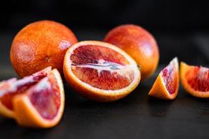 sliced sicilian or bloody oranges on a black slate background photo