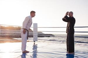los luchadores de karate están peleando en el ring de boxeo de la playa por la mañana