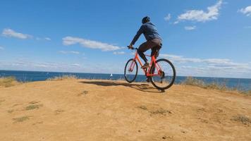 macho joven en la bicicleta con paseo en casco en la playa foto