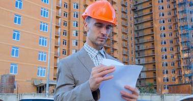 portrait of construction specialist in orange helmet and safety vest against big building photo