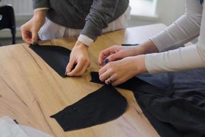 costurera en el trabajo sobre la mesa, sastre mujer trabaja en estudio con ropa foto