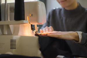 seamstress at work on the table, tailor woman work in studio with clothes photo