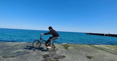 macho joven con monopatín relajándose cerca del mar foto