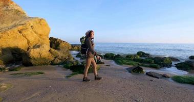 jovem viajante feminina com mochila e câmera de filme retrô viajar nas montanhas de outono perto do mar
