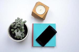 black cellphone on white background, top view of smartphone and interior decorations photo