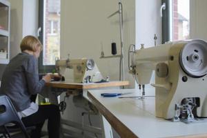 seamstress at work on the table, tailor woman work in studio with clothes photo