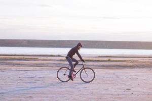 Alone rider on fixed gear road bike riding in the desert near river, hipster tourist bicycle rider pictures. photo