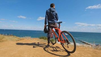 macho joven en la bicicleta con paseo en casco en la playa foto