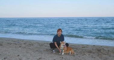 Jeune femme joue avec un chien corgi sur la plage de la mer video