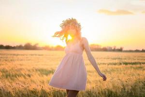 portraits of young woman having good time in wheat field during sunset, lady in head flower wreath during