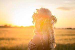 retratos de mujeres jóvenes pasándola bien en el campo de trigo durante la puesta de sol, dama en la corona de flores de la cabeza durante foto