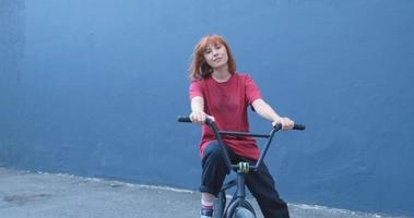 Mujer joven posando con bicicleta BMX al aire libre en la calle