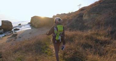 joven viajera con mochila y cámara de cine retro viaja en las montañas de otoño cerca del mar video