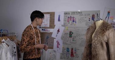 porträt eines asiatischen kleidungsdesigners, der im studio arbeitet. Startup-Kleinunternehmer ist dabei, eine neue Kleiderkollektion zu erstellen. video