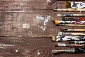 Brushes for painting lie on the old wooden rustic table in the artist's studio photo