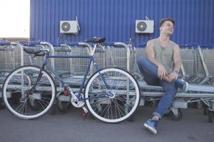 Young ,man walk with fixie bike, urban background, picture of hipster with bicycle in blue colors photo