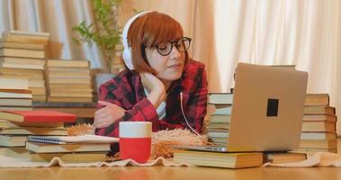 jonge vrouw student die thuis studeert met veel boeken en laptop