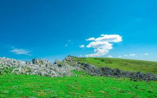 Landscape of green grass and rock mountain in spring with beautiful blue sky and white clouds. Countryside or rural view. Five people trekking on the mountain. Fresh air environment. Eco concept. photo