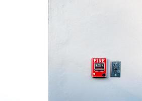 Fire alarm on white concrete wall. Warning and security system. Emergency equipment for safety alert. Red box of fire alarm on wall of school, hospital, factory, office, apartment, or home. Pull down.