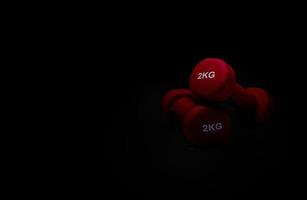 Set of red dumbbells on dark background. A pair of red neoprene dumbbells. Home gym equipment for exercise at home. Weight training equipment for sculpt arms, shoulders, back, and legs. photo