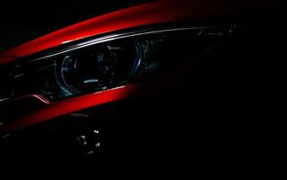Closeup headlight of shiny red luxury SUV compact car. Elegant electric car technology and business concept. Hybrid auto and automotive concept. Car parked in showroom or motor show. Car dealership. photo